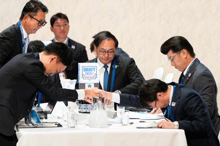 握手をかわす長谷川部長（左）。三浦監督も真剣に資料に目を落とす　©Nanae Suzuki