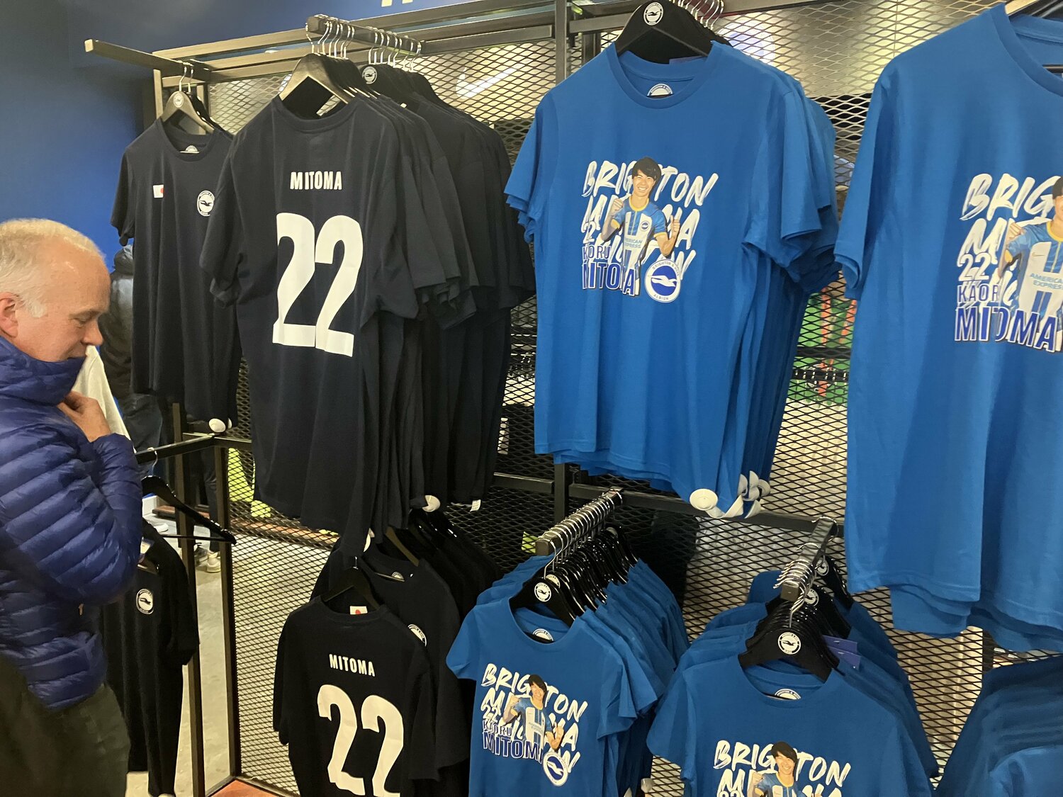 右のブルーのTシャツがオリジナルデザインの三笘Tシャツ。「おそらく店一番の人気商品になると思う」（店員のジェイミー・ハリアさん）