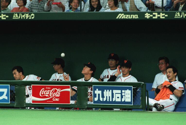 写真は1994年10月。先発メンバーから外され、ベンチでボールを放り投げる松井秀喜。右は長嶋一茂、落合博満　©JIJI PRESS