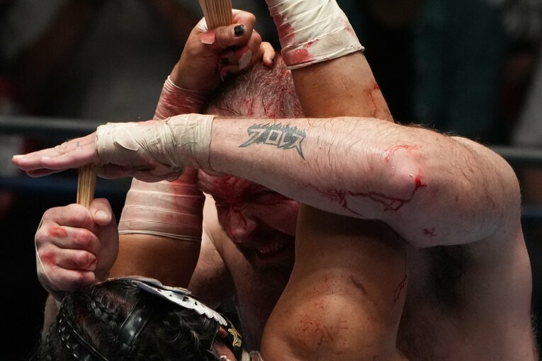 「はんぶんこ」した竹串をお互いの頭部に突き刺し合うエル・デスペラードとジョン・モクスリー