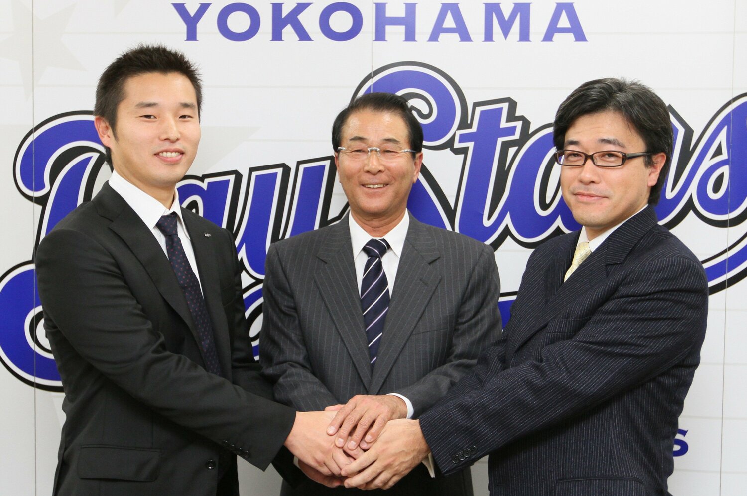 GM就任記者会見で、春田真オーナー（右）、池田純球団社長（左）と握手する高田繁　©JIJI PRESS
