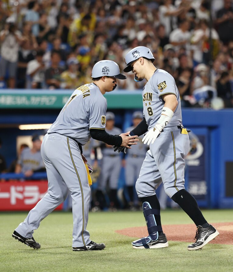 ホームランを放った佐藤輝明を出迎える森下翔太。打撃3部門の上位は「アイブラック兄弟」が独占している　©JIJI PRESS