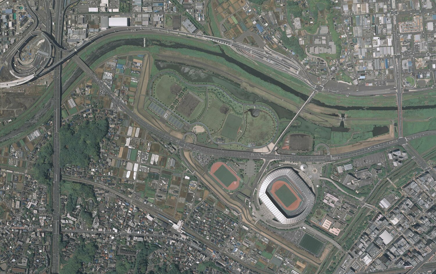 2019年の小机駅周辺の航空写真。小机駅は画面真ん中下の白い建物。田園地帯だったところに、立派な日産スタジアムが出来たことがよく分かる　出典：国土地理院の空中写真