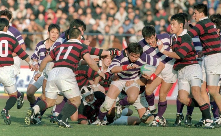 第33回大学ラグビー選手権で早稲田大を破り、連覇を達成した明治大。ボールを抱えて突破する神鳥新監督と、後方でその行方を見守る田中前監督　©︎Sankei Shimbun