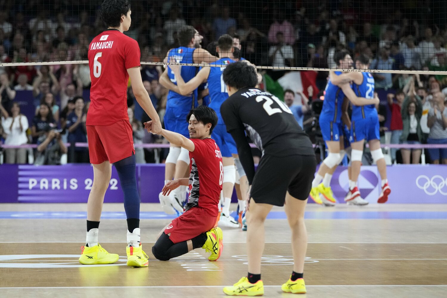 コートに座り込む関田誠大に手を差し伸べる山内晶大。ネットの向こうでは、イタリア代表が“奇跡の逆転勝利”に歓喜している　©︎AP/AFLO