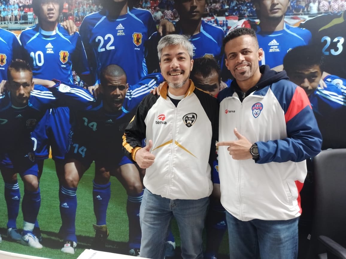 左がASB会長のパウロ・シゲマサ・シャビエル。背景は、2006年ワールドカップGSクロアチア戦前の集合写真