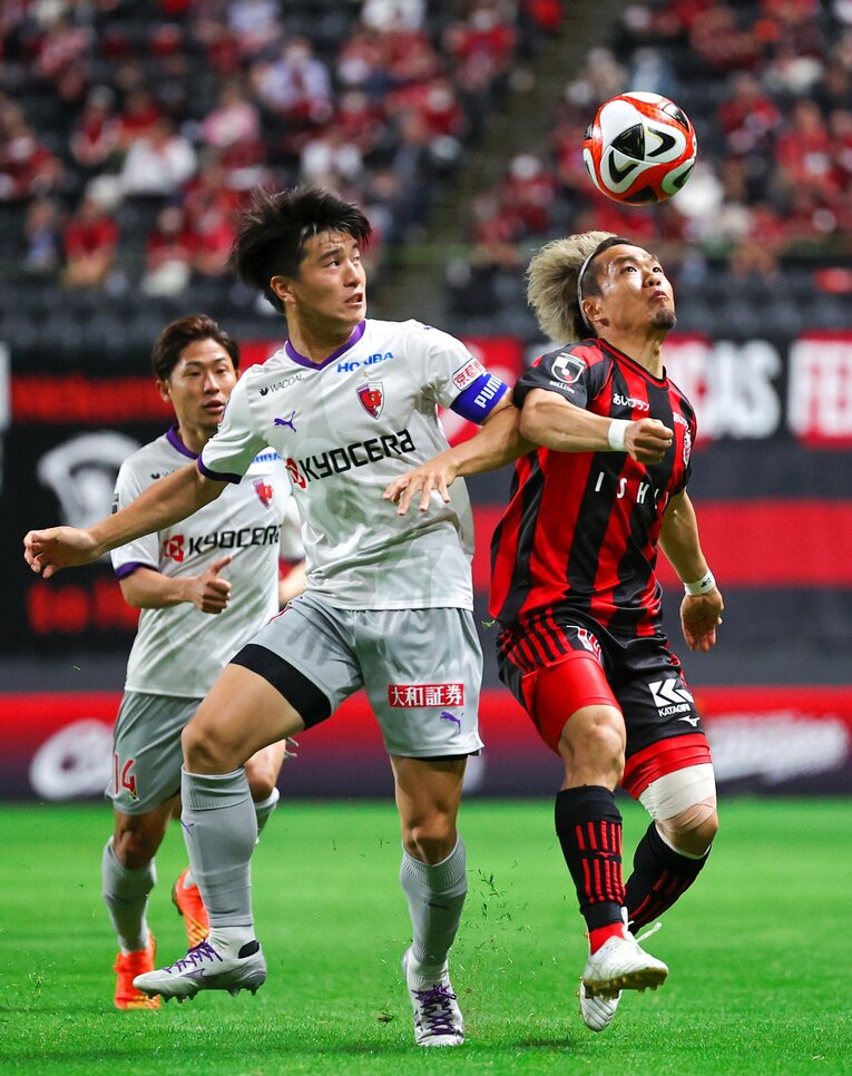 左膝にテーピングを巻いてプレーする駒井善成（右）　©︎JIJI PRESS