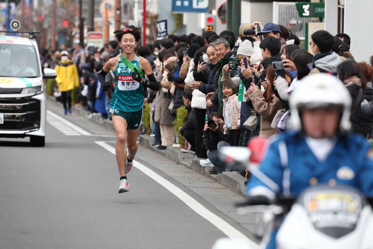 沿道の応援を目に焼きつけたかった、と用意していたサングラスをかけることなく笑顔で走り切った白石光星　©JMPA
