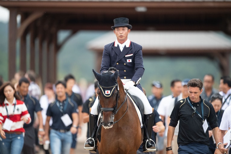 世界選手権で待機馬場からアリーナに向かう原田とエジスター（中央）、 ドイツ人トレーナーのクリストフ・コシェル（右）