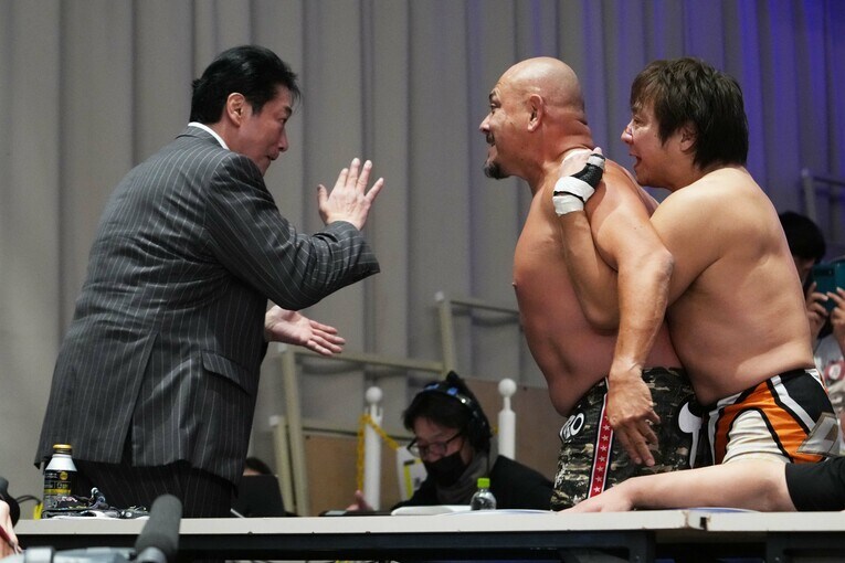 小島聡に羽交い絞めされた太陽ケアにチョップを見舞う放送席の小橋建太　©Essei Hara