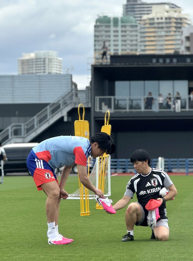 上田綺世（左）に替えのスパイクを渡すサッカー日本代表の用具係の山根威信さん ©JIJI PRESS