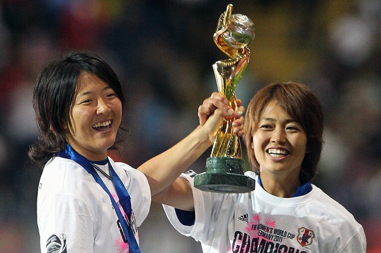 女子W杯を手に、笑顔の永里優季と安藤梢　©AFP/JIJI PRESS