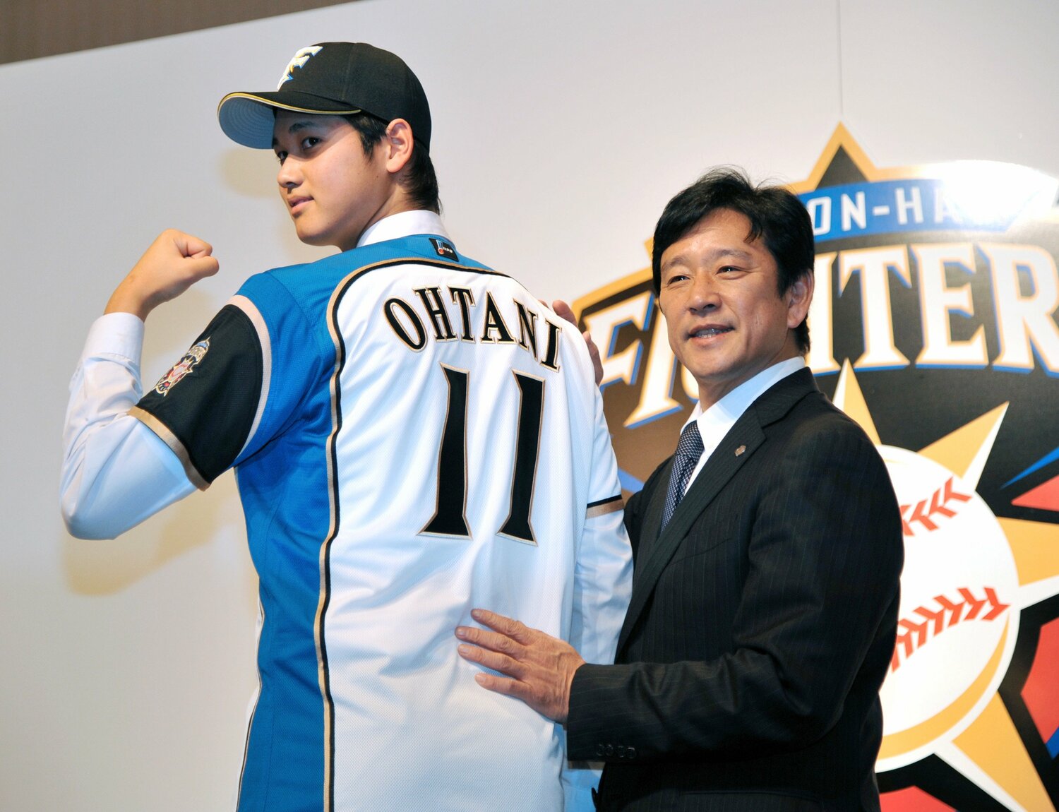 日本ハムの入団会見でユニフォームに袖を通した大谷翔平と栗山英樹監督　©︎JIJI PRESS