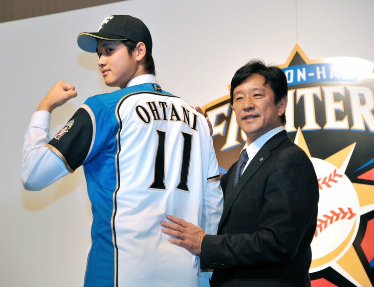 日本ハムの入団会見でユニフォームに袖を通した大谷翔平と栗山英樹監督　©︎JIJI PRESS