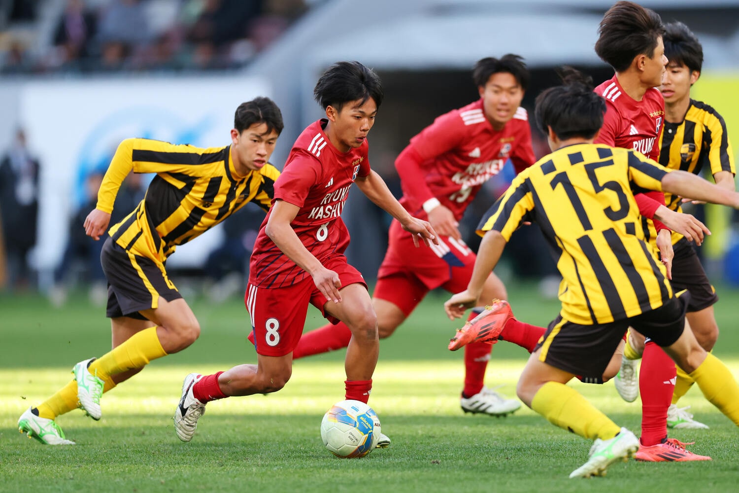 相手に囲まれながらも、フットサルで養った巧みなボールコントロールで抜き去っていく亀田。「（フットサルで多用する）足裏を使うことが癖になると人工芝や天然芝でやるサッカーではスピードアップしにくくなるので、なるべくアウトサイドを使うようにした」　©︎Naoki Morita/AFLO SPORT