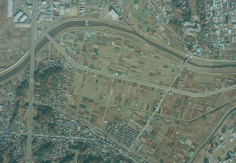 1984年の小机駅周辺の航空写真。小机駅は画面真ん中下。画面上を左右に流れるのが鶴見川。当時の駅北側には田園地帯が広がる　出典：国土地理院の空中写真