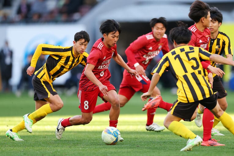 相手に囲まれながらも、フットサルで養った巧みなボールコントロールで抜き去っていく亀田。「（フットサルで多用する）足裏を使うことが癖になると人工芝や天然芝でやるサッカーではスピードアップしにくくなるので、なるべくアウトサイドを使うようにした」　©︎Naoki Morita/AFLO SPORT