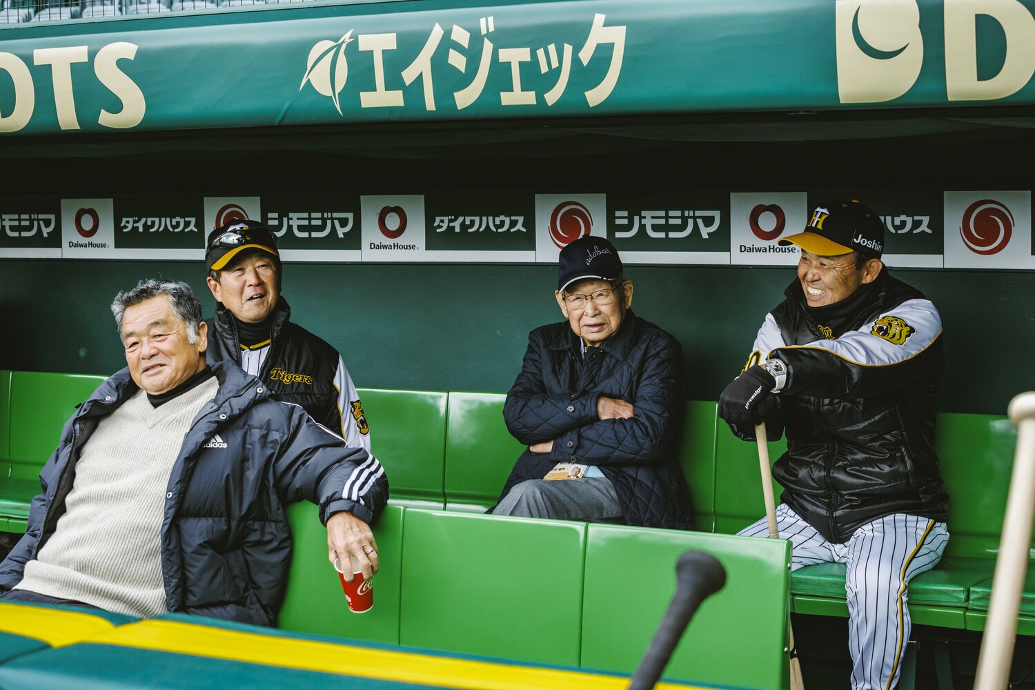 ベンチで話し込む（左から）川藤幸三氏、平田ヘッドコーチ、吉田義男氏、岡田監督　©︎Kiichi Matsumoto