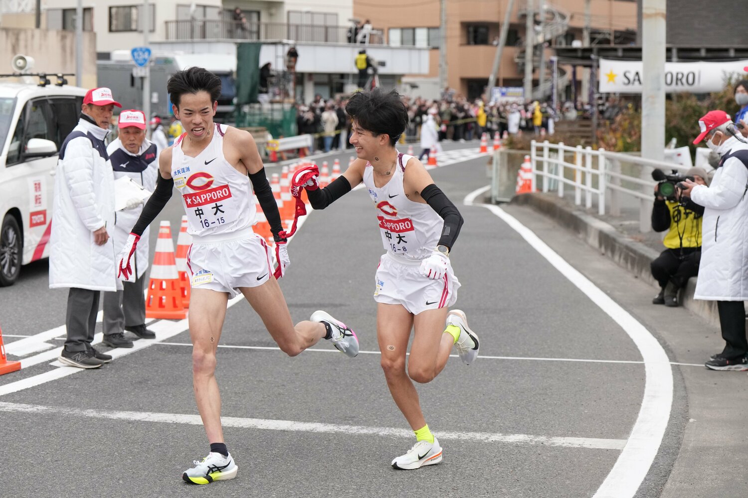 平塚中継所で、タスキをつなぐ中大7区の岡田開成(1年)と8区の佐藤大介(1年) ©JMPA