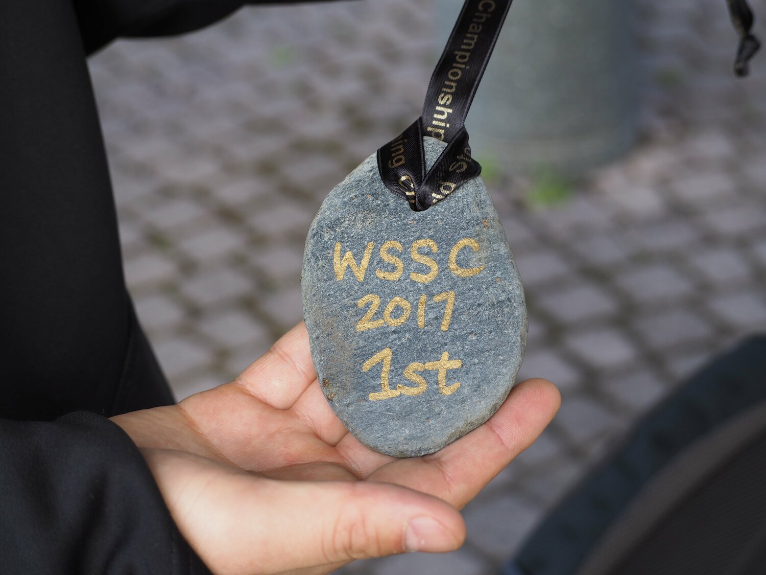 水切り世界選手権の優勝メダルは石。結果発表で「ダイスケハシモト」と呼ばれ、マイクを渡されると「アイム、ケイスケ」と開口一番で訂正 ©Yu Saito