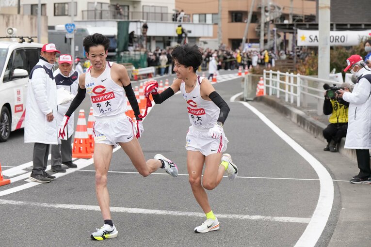 平塚中継所で、タスキをつなぐ中大7区の岡田開成（1年）と8区の佐藤大介（1年）　©JMPA