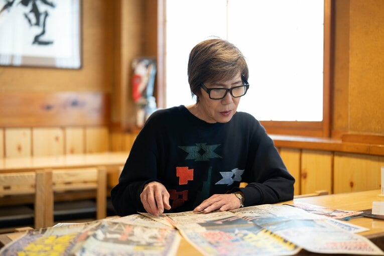 ジャッキー佐藤の死去を報じる当時の新聞を読むマキ上田　©Shiro Miyake