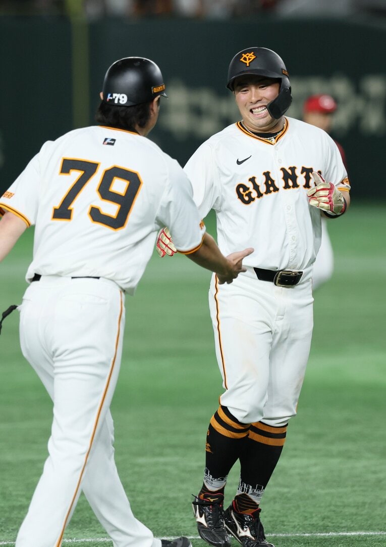 8月22日の広島戦で先制タイムリーを放ち、ベンチに戻る際に亀井善行コーチから祝福された浅野　©︎JIJI PRESS