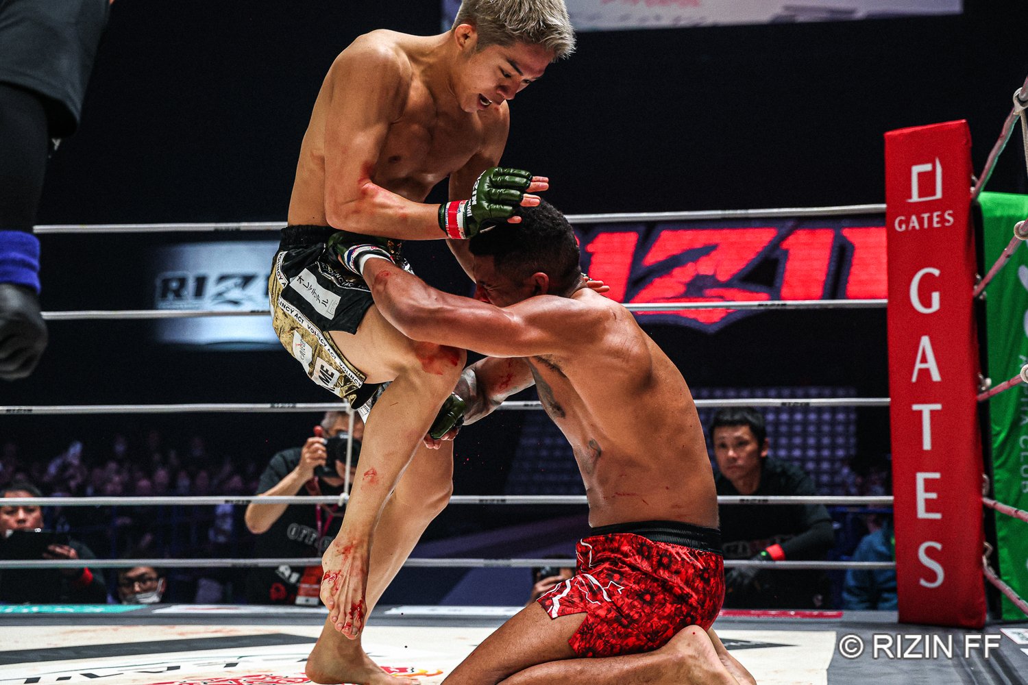 KO寸前にまで追い込まれ、たまらずコスチュームをつかむミックス。秋元強真の足には返り血　©RIZIN FF