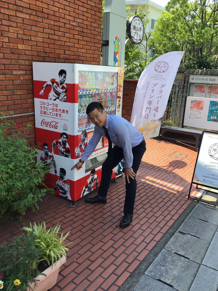 自動販売機にプリントされた元同僚のW杯日本代表FBトゥポウを指差す豊田（写真：本人提供）
