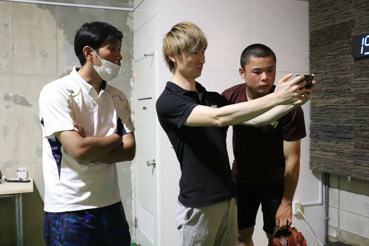 石原投手（右）とともに動画をチェックする北川トレーナーに耳を傾ける羽鳥監督　©Yu Takagi