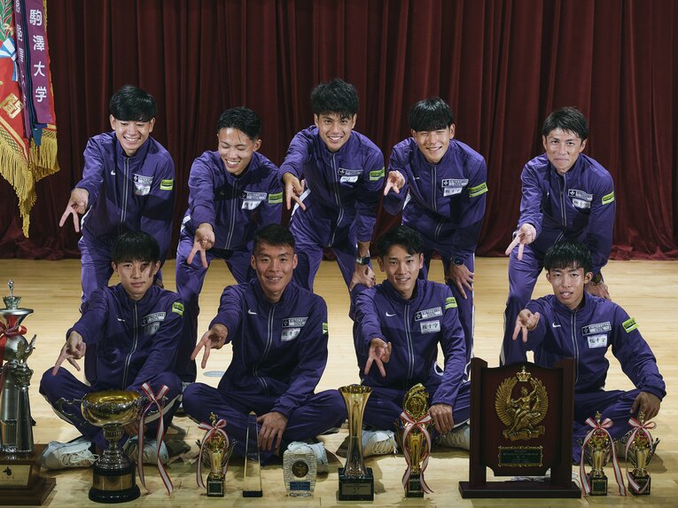 選手たちと一緒に「ギャルピース」をする藤田敦史監督（右上）。選手たちに混ざっても違和感ない若さ　©Yuki Suenaga