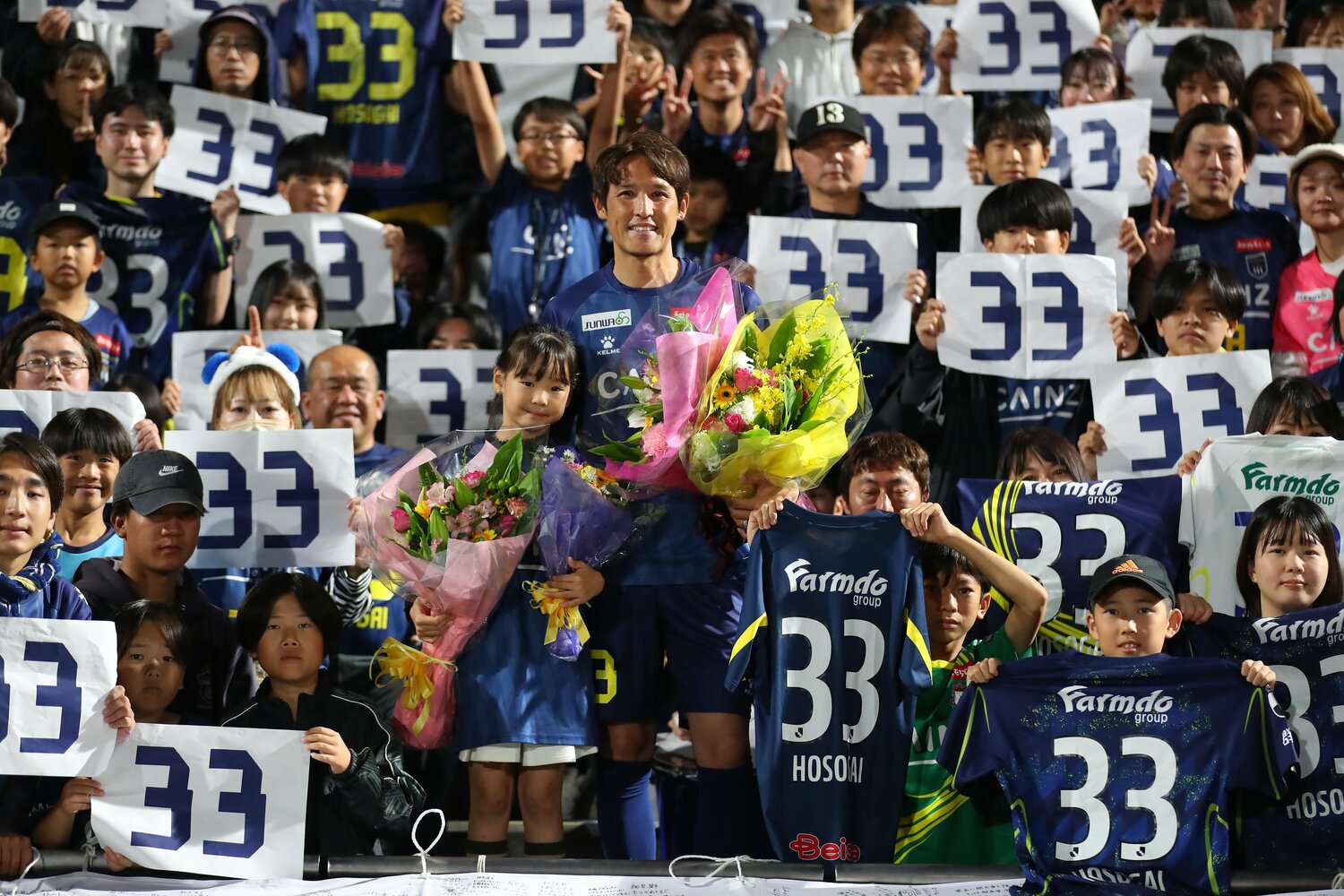 娘とともに群馬サポーターのなかで花束をもつ細貝　©︎J.LEAGUE