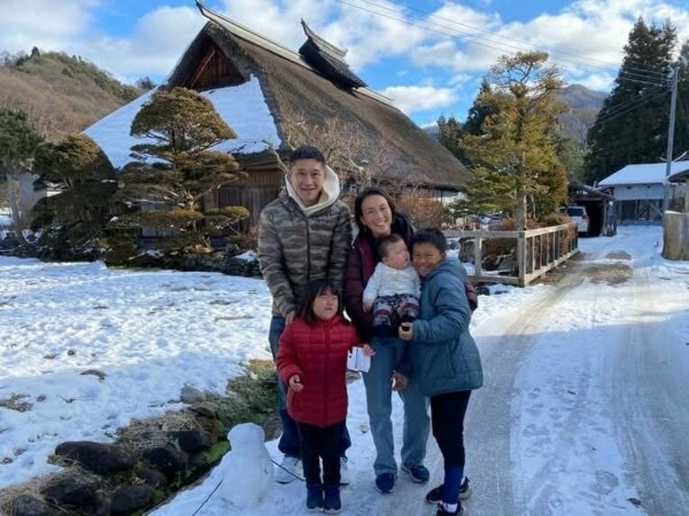 沼田市の茅葺屋根の家の前で　※家族提供