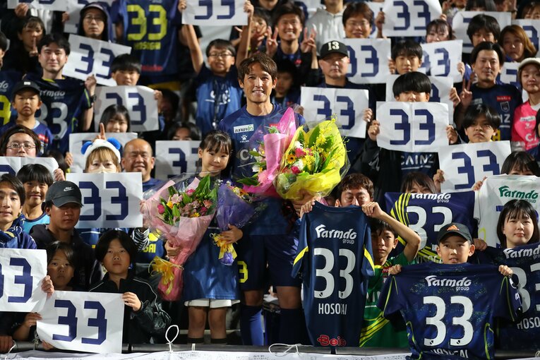 娘とともに群馬サポーターのなかで花束をもつ細貝　©︎J.LEAGUE