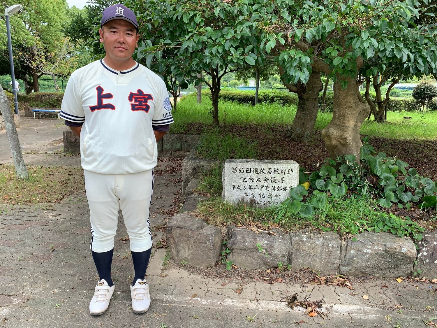 1993年センバツ優勝の記念樹と石碑の前に立つ村田監督 ©Katsuharu Uchida