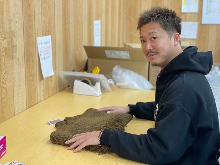 在庫の段ボールに囲まれながら作業する横山