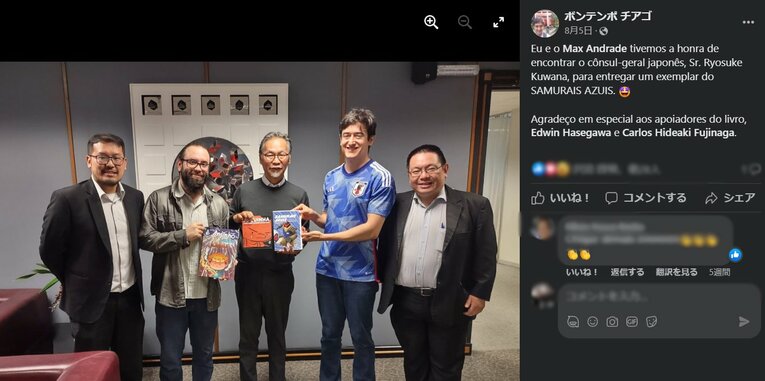 在サンパウロ日本総領事館の桑名良輔総領事に日本のフットボールに関する自著を進呈したチアゴ・ボンテンポ記者（サムライ・ブルーのユニフォーム姿）　※Facebookより