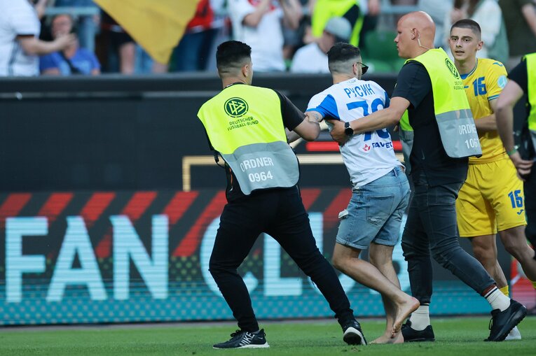 突如乱入した観客に警備員スタッフがチャージして取り押さえる　©dpa/JIJI PRESS