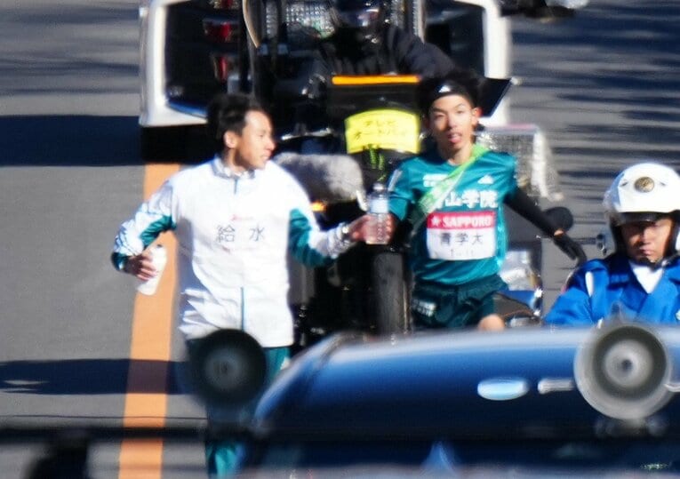 ５区、弟の然（左）から水を受け取る青学大の黒田朝日　©JIJI PRESS