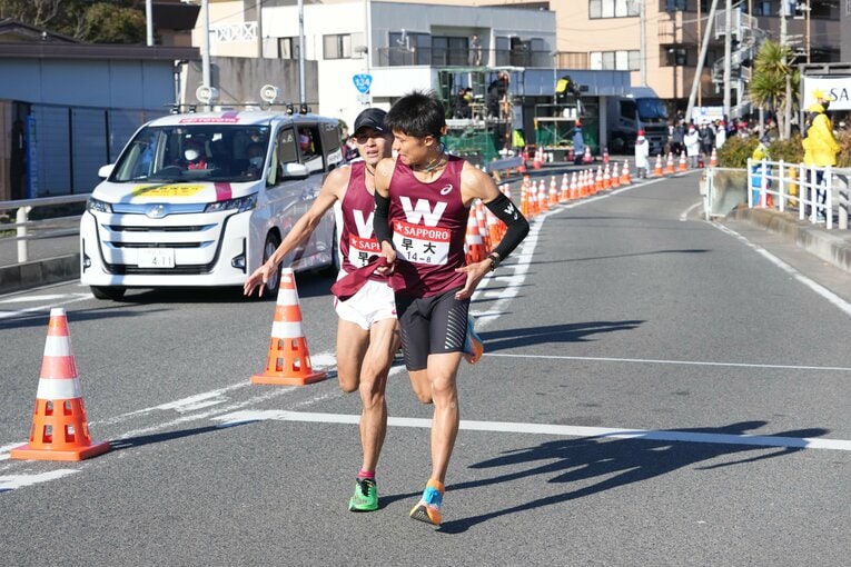 平塚中継所で、たすきをつなぐ早大7区の鈴木創士（左、4年）と8区の伊福陽太（2年）　©JMPA
