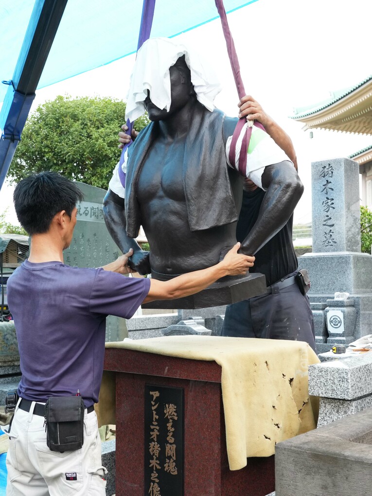 慎重に台座に降ろされる猪木像