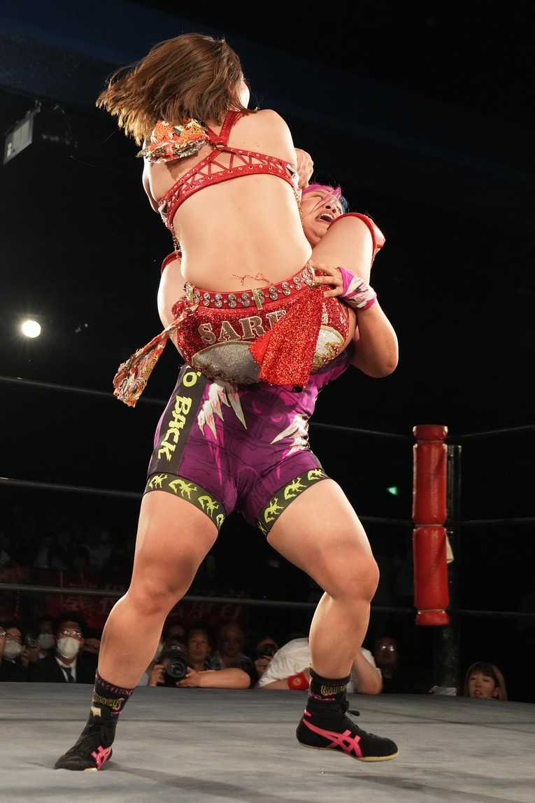 三角絞めを怪力で担ぎ上げ、コーナーに運ぶ橋本千紘