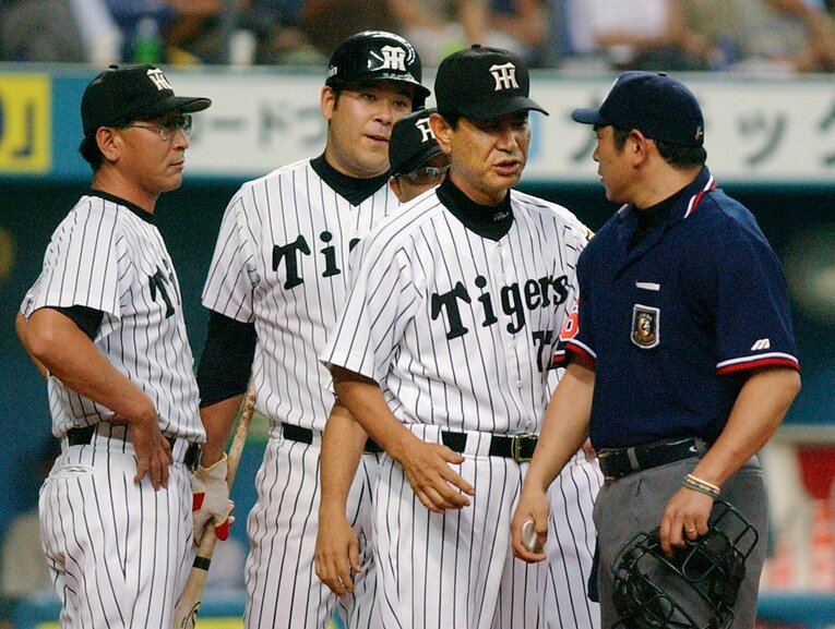 2003年、打席での判定に不服そうな表情を浮かべて球審・真鍋を呼び止めた伊良部（左から２人め）。ただならぬ空気にあの星野監督が思わず止めに入った　©︎JIJI PRESS