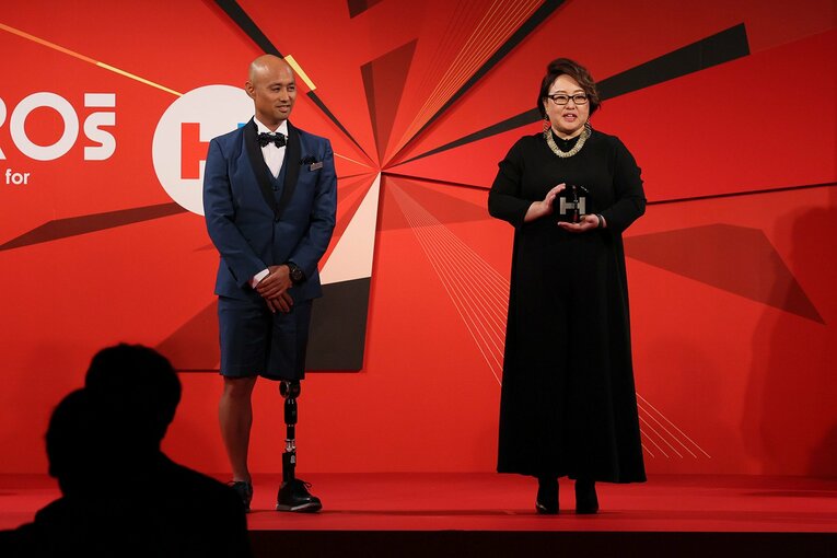 パラリンピックメダリストの山本篤さん（左）から、トロフィーを受け取ったオットーボック・ジャパンの深谷香奈さん