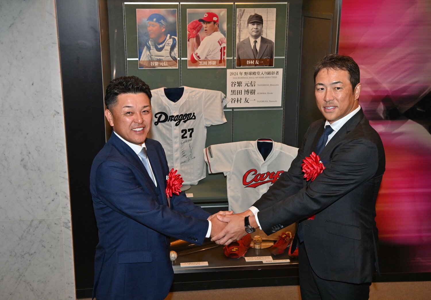 記念展示の前で握手する、競技者表彰のプレーヤー部門で殿堂入りした谷繁と黒田（代表撮影）　©JIJI PRESS