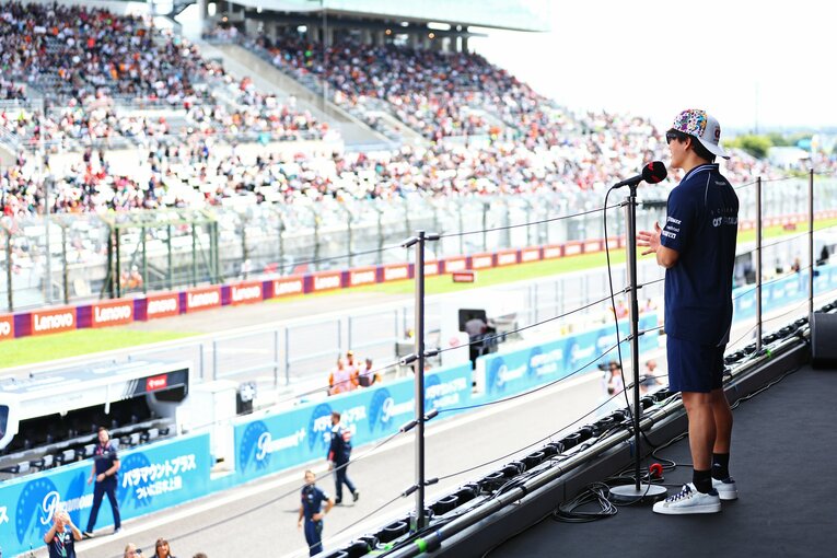 鈴鹿サーキットの表彰台から、ファンに向け来季のアルファタウリ残留を報告する角田　©Getty Images / Red Bull Content Pool
