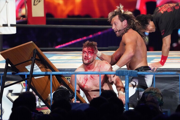 ケニー・オメガは流血したウィル・オスプレイを容赦なく机に叩きつける