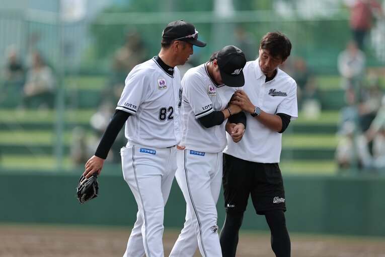トレーナーに付き添われてベンチ裏に下がる本前　©︎Chiba Lotte Marines