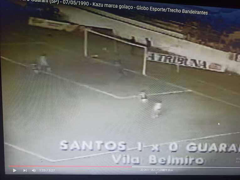 カズと戦った試合の映像。手前の白いユニフォームがカズで、右サイドのあまり角度がない位置から放った右足シュートがファーサイドのネットに吸い込まれつつある。画面上部に、「1990年5月7日、サントス１－グアラニー０。カズがスーパーゴールを決めた」と記されている