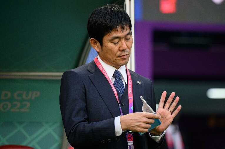 ベンチ前でメモ帳を読み返す森保一監督。ドイツに圧倒された前半は動かず、ハーフタイムに大胆なシステム変更を行った ／ photograph by Getty Images